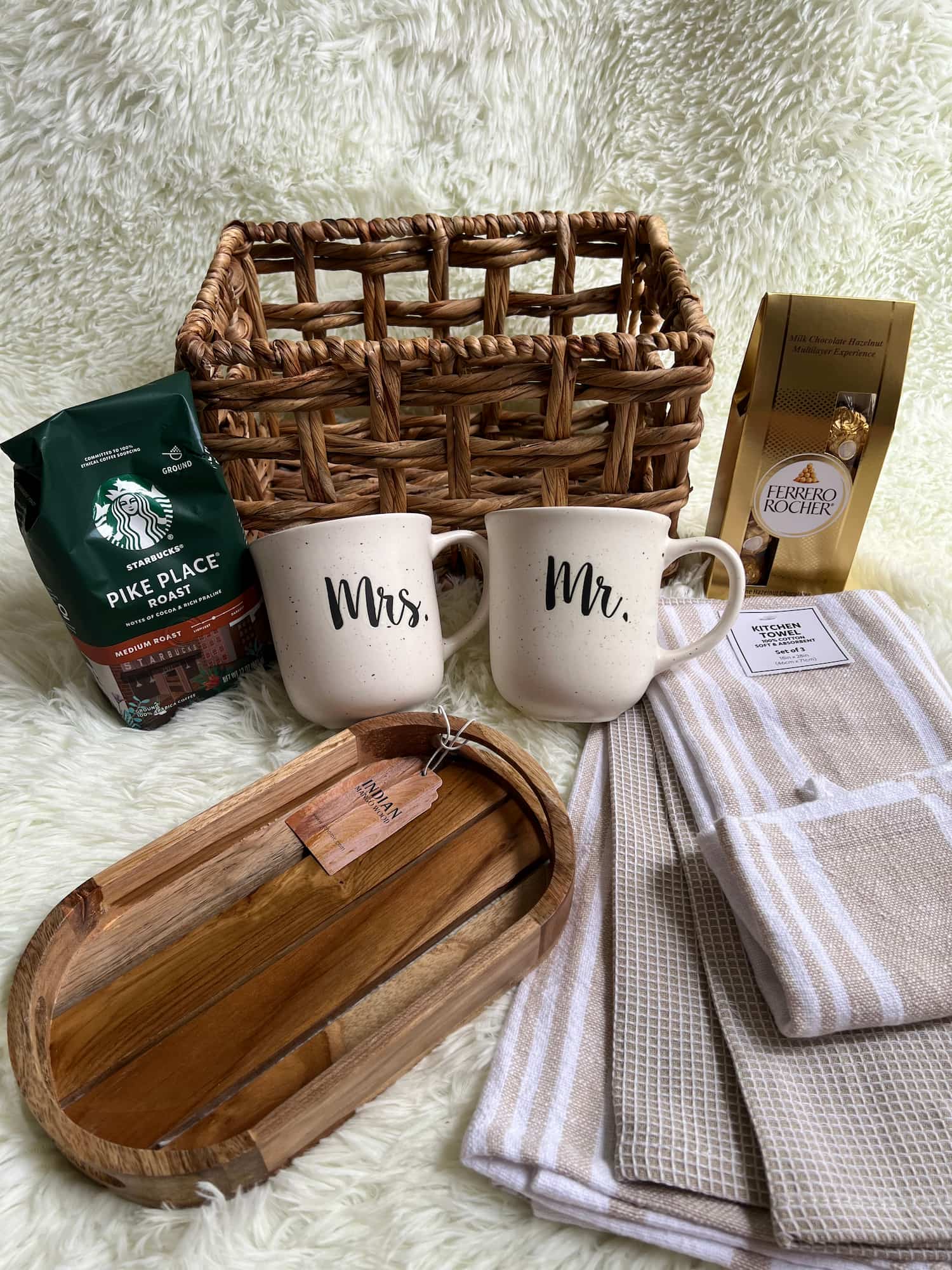 Wicker Basket, Set of 'Mr.' and 'Mrs.' mugs, wooden tray, and coffee packaging on a textured surface