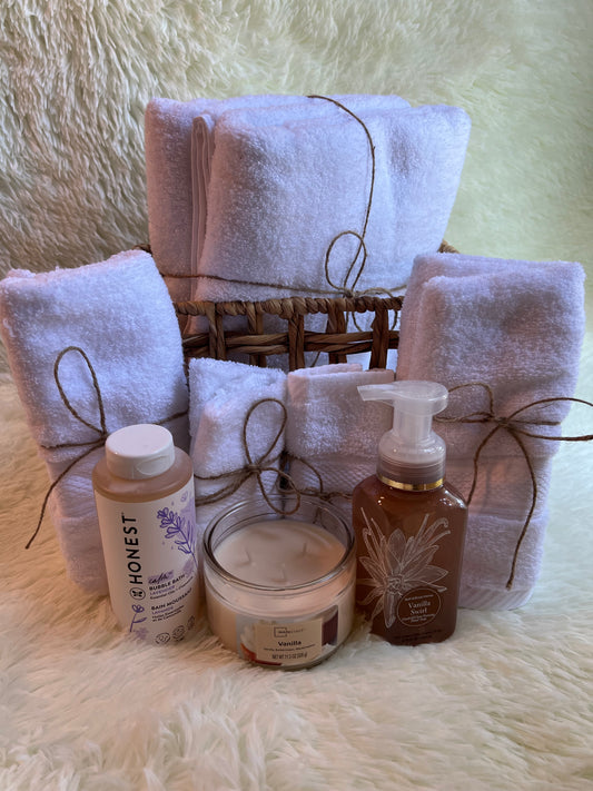 Set of folded towels and skincare products on a textured surface. Bath gift set