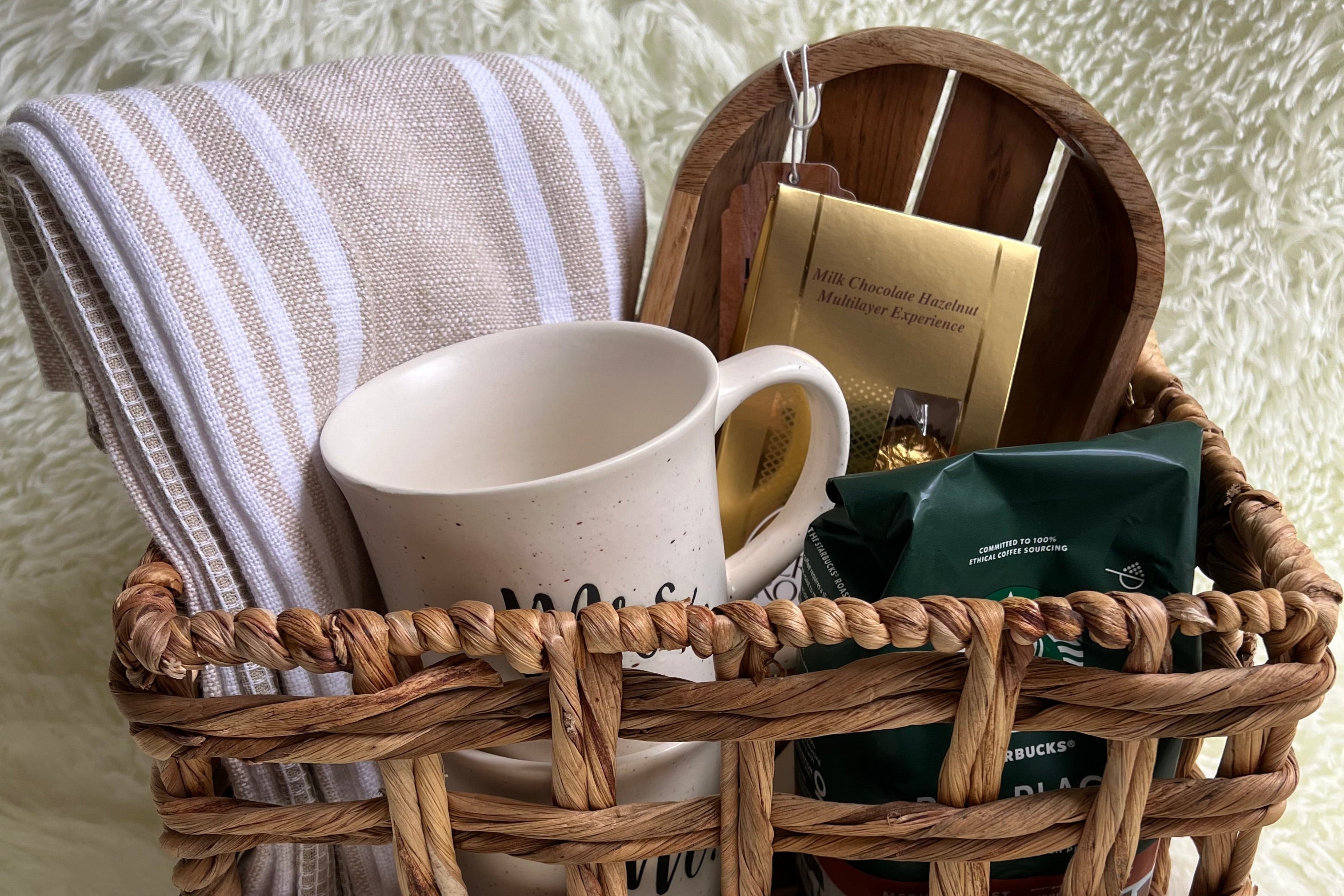 Woven basket with a cup, towel, and books on a textured surface