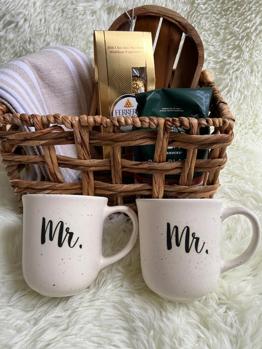 Rattan basket with aromatic coffee products and 'Mr.' mug set on a fluffy white surface